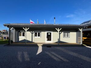 Budynek drewniany z flagami.