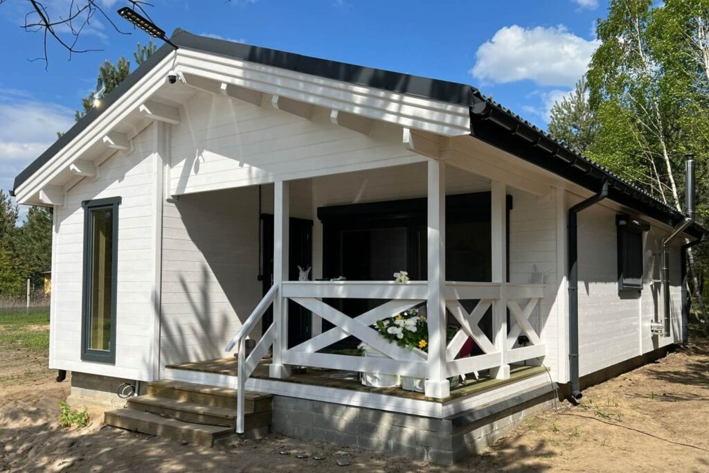 Drewniany dom z białymi ścianami i werandą.
