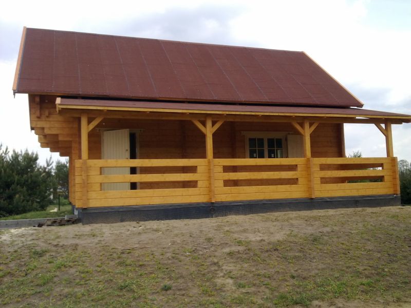 Drewniany, zadaszony budynek z werandą.