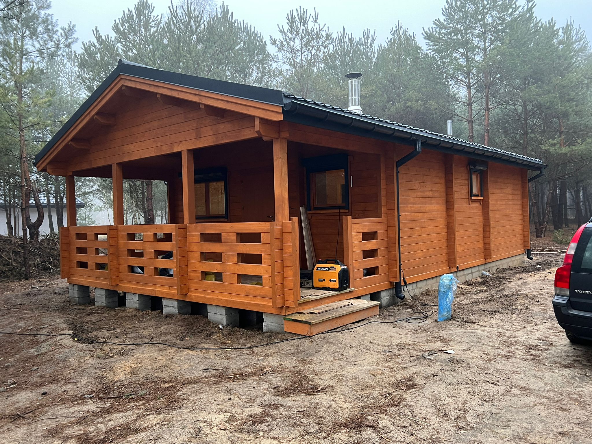 Drewniany domek z zadaszonym tarasem.