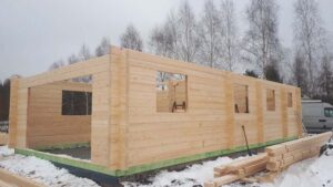 Drewniany budynek w budowie na śnieżnym podłożu.