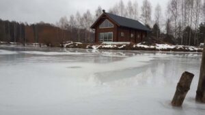 Drewniany dom nad zamarzniętym jeziorem.