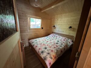 Mała drewniana chatka z łóżkiem.