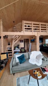 Drewniany, przytulny pokój z sofą i półpiętrem.