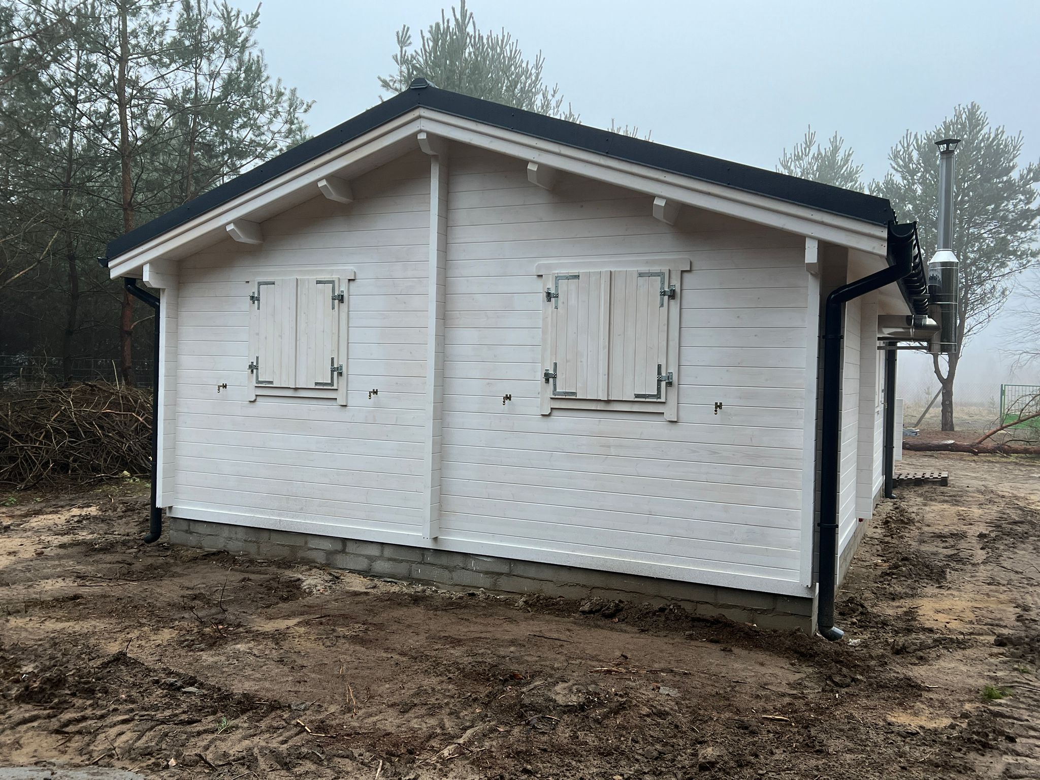 Biały drewniany domek z czarnym dachem.