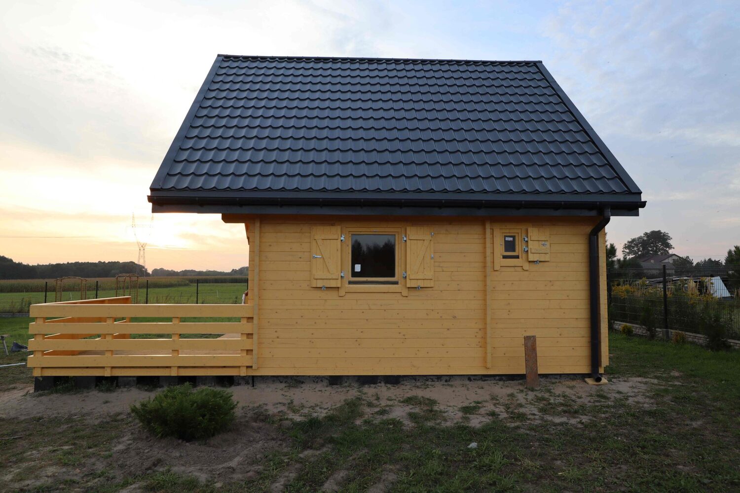 Mały drewniany domek na wsi z czarnym dachem.