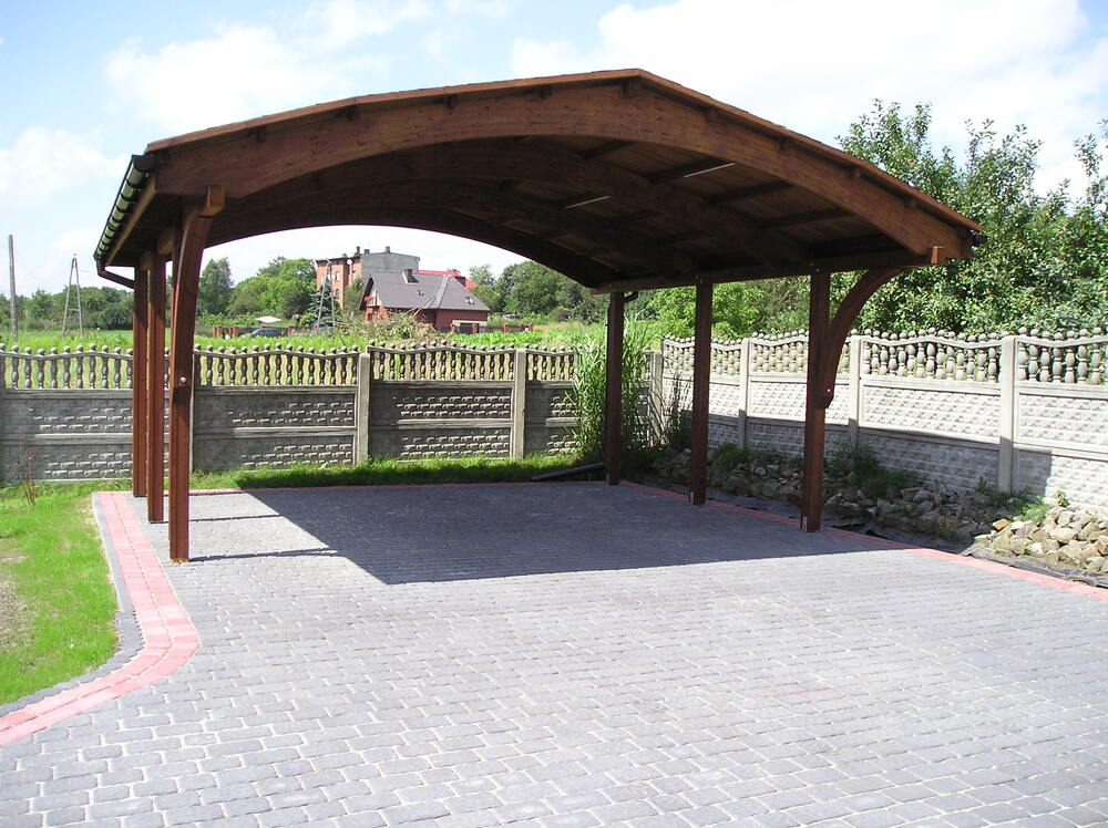 Drewniana konstrukcja, cegłany płot, brukowany plac.