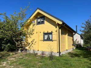 Drewniany, żółty dom z oknami w ogrodzie.