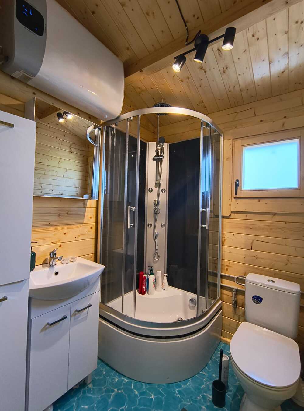 Łazienka z kabiną prysznicową i drewnianą zabudową.