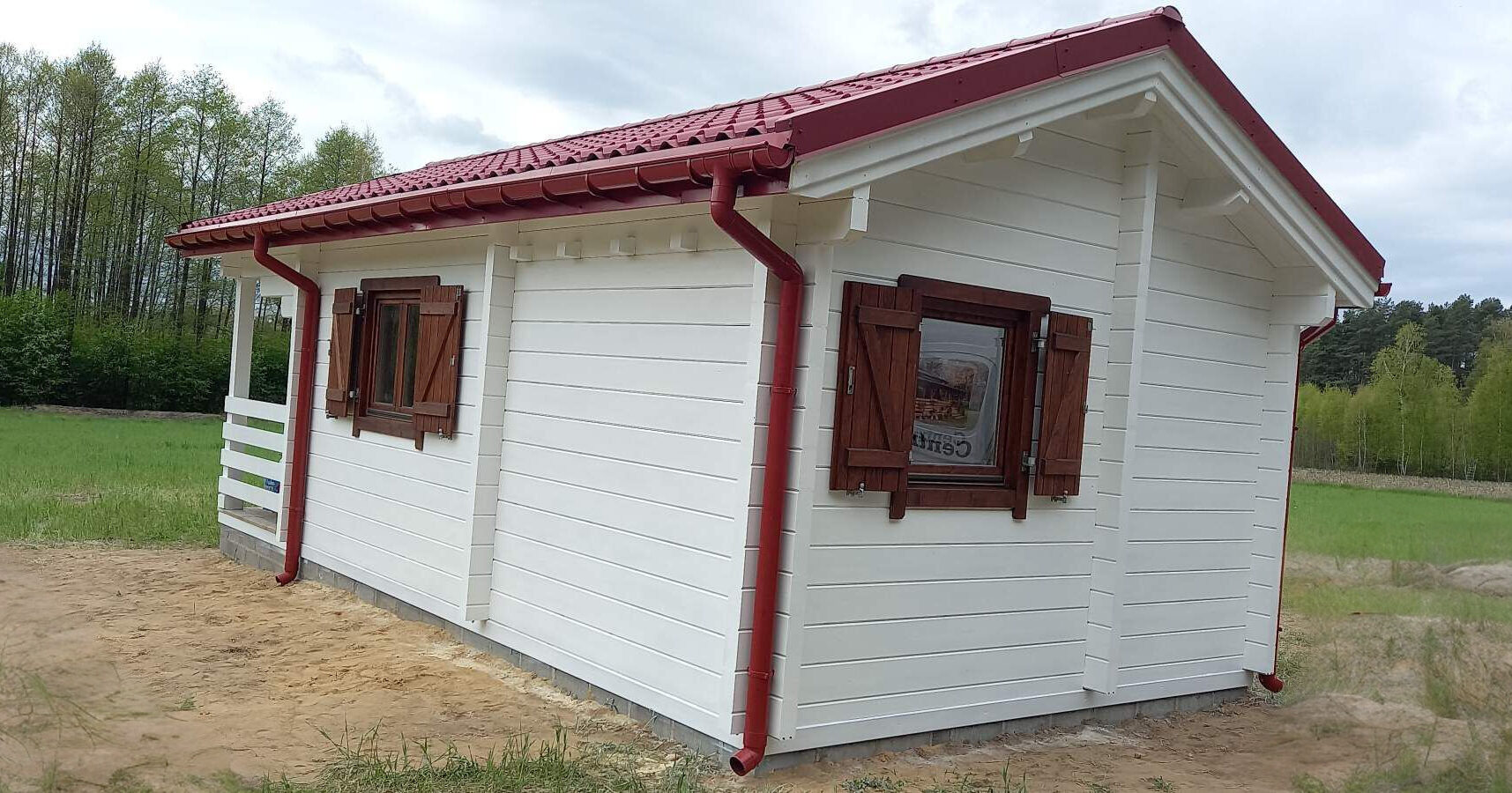 Biała chatka z czerwonym dachem.