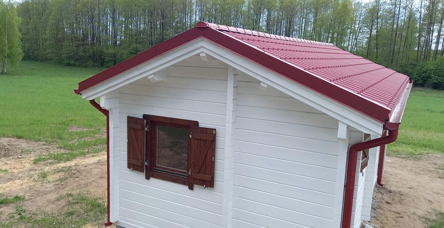 Biała chatka z czerwonym dachem.