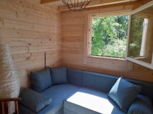 Przestrzeń wewnętrzna z drewnianymi ścianami, oknem, kanapą.