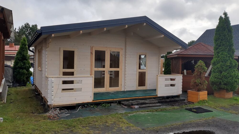 Mały drewniany domek na podwyższonym podłożu.