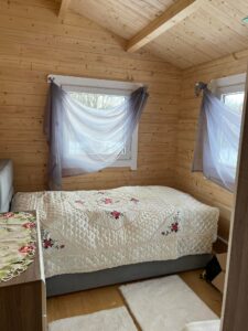 Drewniane wnętrze, łóżko z kwiecistą narzutą.