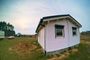 Mały drewniany dom z czerwonym autem.