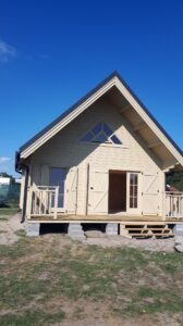 Drewniany dom z krzywą dachem.