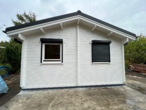 Biały dom drewniany z czarnym dachem.