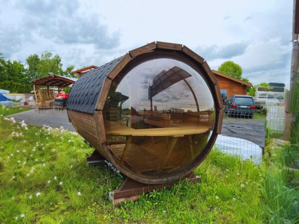 Drewniana, okrągła sauna na trawie.