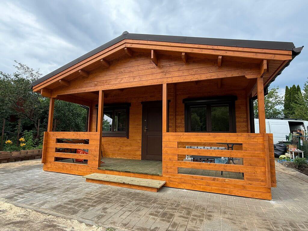 Drewniany domek ogrodowy z dużym zadaszeniem.